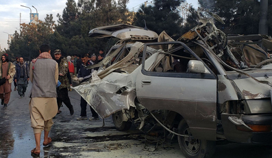 People gather next to a damaged bus damaged in a deadly bomb blast in Kabul